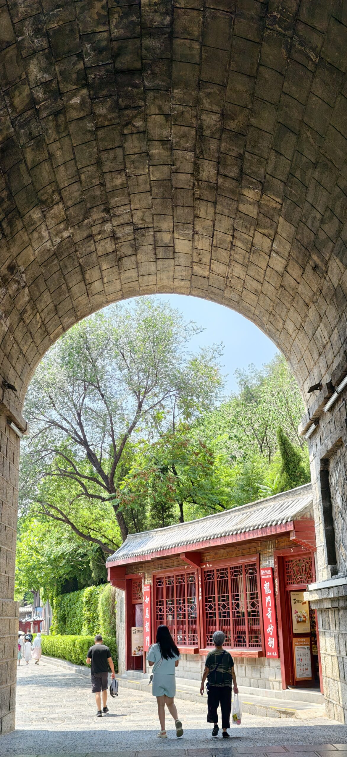 穿过石拱，景区内的红墙与传统院落从豁口处显现
