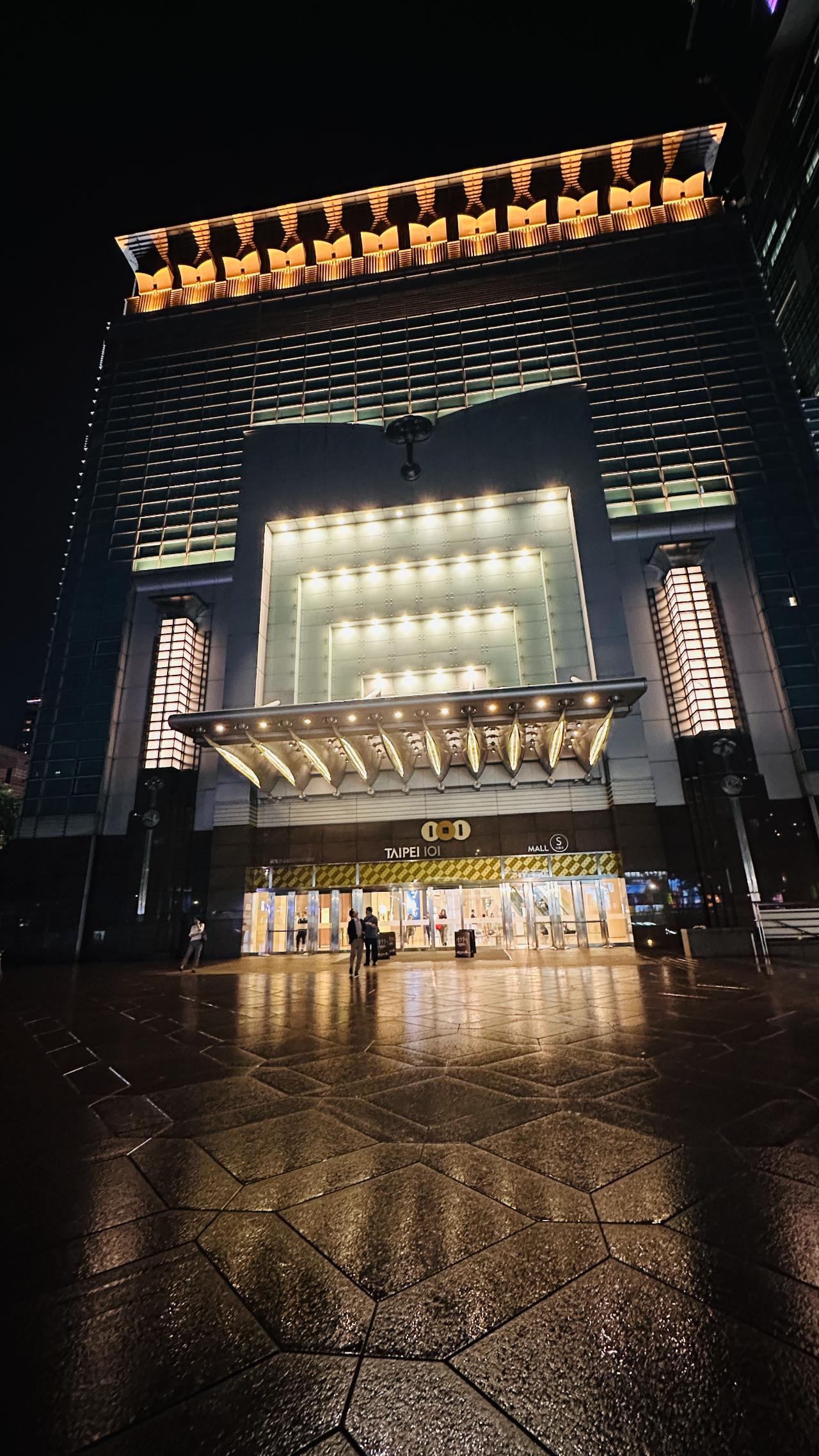 从101下来后经过旁边商场入口，雨夜地面把灯光反射得很亮
