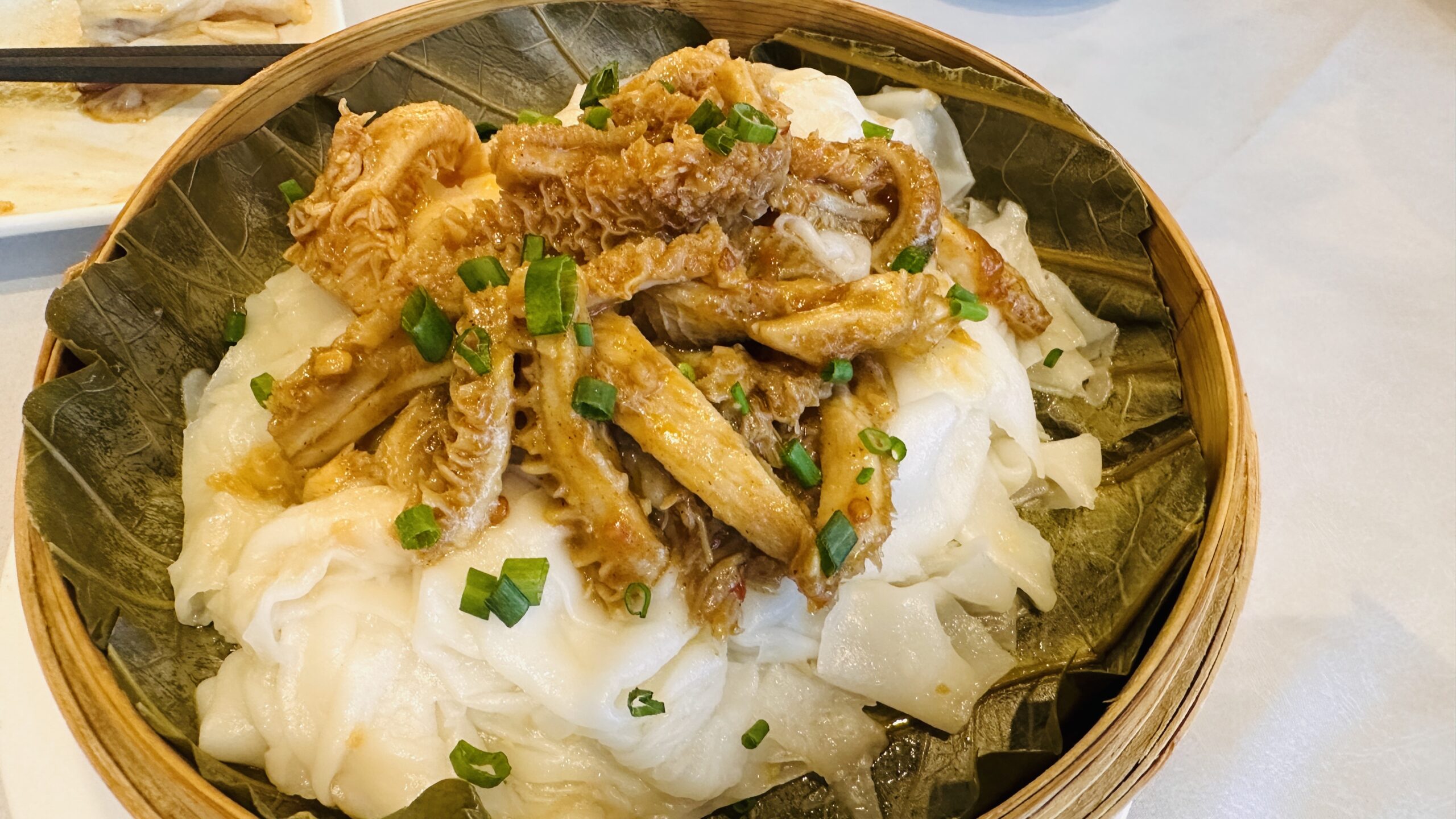 荷叶蒸笼中的宽粉铺上酱香蜂窝牛肚，汤汁浓郁。