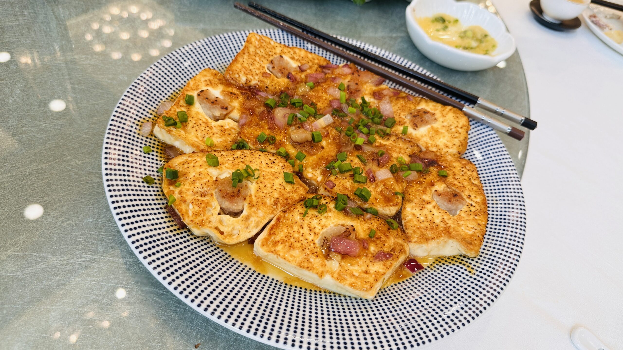 煎至金黄的豆腐方块码成一盘，上面铺着肉粒和葱花。
