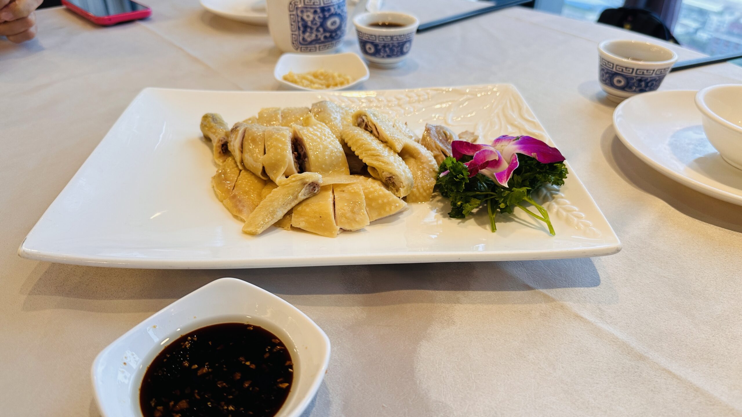 白切鸡切块整齐，配姜葱蘸料与茶道小杯。