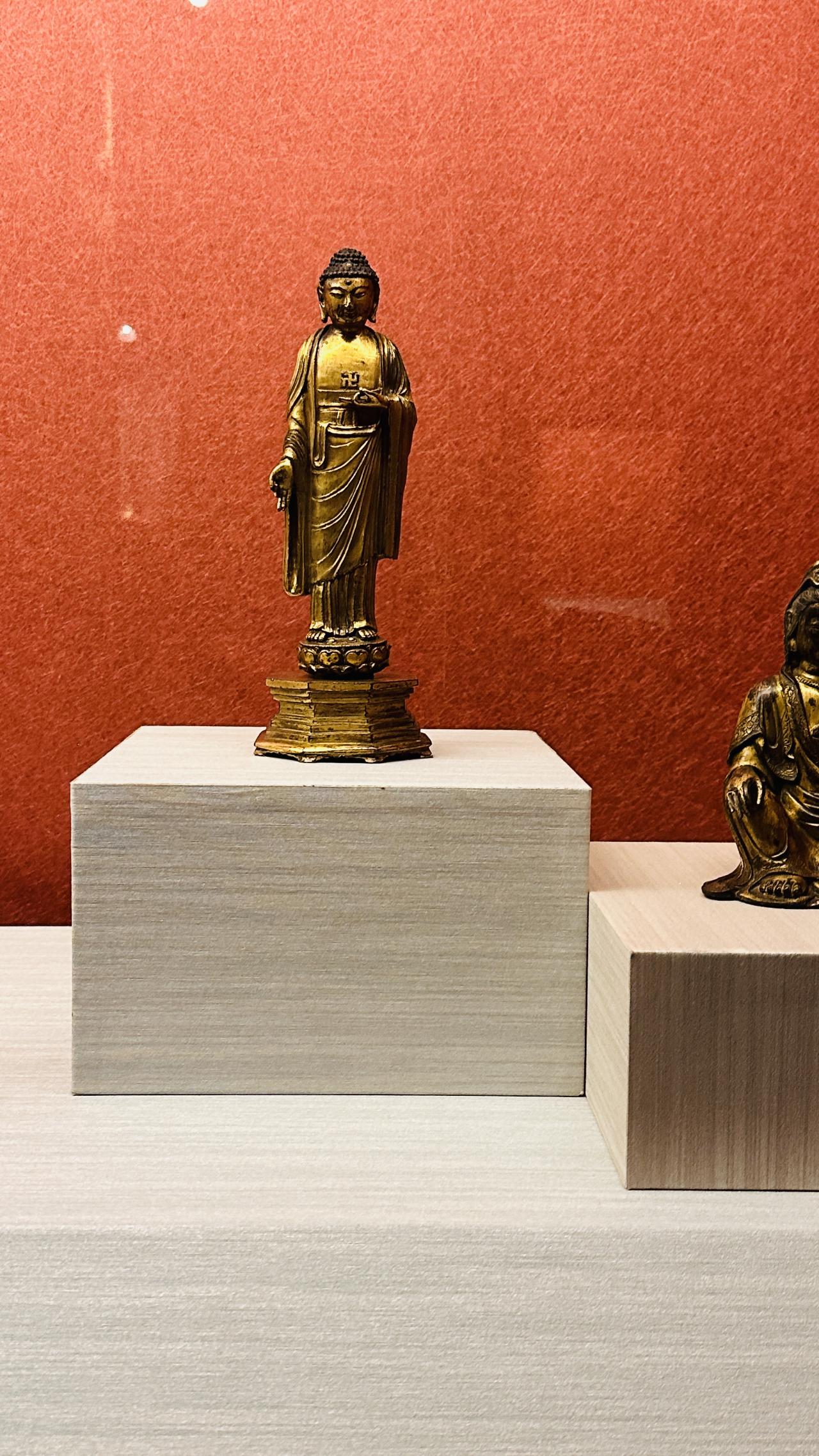 佛像在展柜里静静站着，像从旧时间里走到灯下